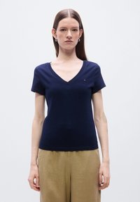 Μπλε βαμβακερό t-shirt με V γιακά, κοντά μανίκια, εφαρμοστή γραμμή και μικρό λογότυπο στο στήθος. Ομαλή υφή, casual στυλ.