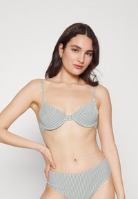Conjunto de bikini riscado com parte de cima com aro e almofadada e parte de baixo de cintura alta. Cores incluem verde-claro e branco. Textura de tecido suave.