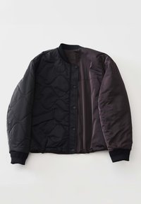 Veste bomber noire matelassée avec des boutons-pression, des poignets et un col côtelés, et une poche diagonale sur le côté gauche.
