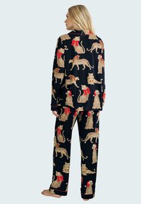 Navy pajama set with a playful leopard print adorned with red ribbons and holiday accents. Soft fabric with long sleeves and relaxed fit.