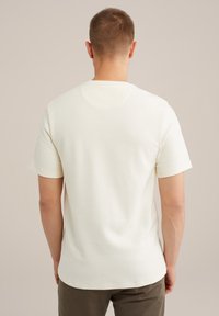 Tricou alb texturat cu mâneci scurte și guler rotund, asortat cu pantaloni verzi măslinii, văzut din spate.
