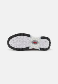 Shoe sole featuring a black rubber border, translucent white midsole with circular grips, and a textured white surface with specks.