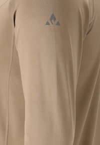 Beige vochtregulerende langemouwen shirt met een gladde textuur en platte naden. Heeft een subtiel grijs logo op de schouder.