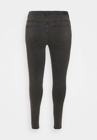 Black skinny jeans with a smooth texture, featuring two back pockets and stitched accents. The design is form-fitting, tapering at the ankles.