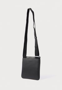 Μαύρη δερμάτινη τσάντα χιαστί με ορθογώνιο σχήμα, κλείσιμο με φερμουάρ και υφή στην επιφάνεια · διαθέτει φαρδιά υφασμάτινη λουρίδα και ασημένια μεταλλικά στοιχεία.