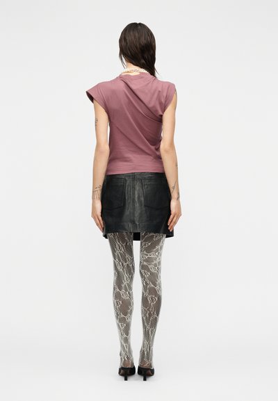 Violetti lyhythihainen paita, jossa laskostettu selkä, musta nahkainen minihame, kuviolliset harmaat käärmekuvioiset sukkahousut ja mustat korkokengät.