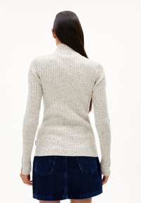 Lichtgrijze geribbelde trui met een hoge kraag en gestructureerde afwerking, gecombineerd met een donkerblauwe corduroy rok met twee achterzakken.