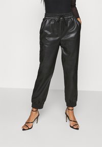 Joggers en cuir noir avec taille élastique, cordon de serrage réglable et poignets côtelés. Dispose de poches latérales et d'une texture lisse et brillante.