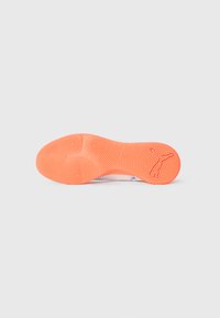 Semelle en caoutchouc texturé orange vif d'une basket, montrant des motifs circulaires et un logo Puma sur la section du talon.
