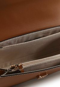 Borsa a tracolla in pelle sintetica marrone con una texture liscia. L'interno presenta una fodera beige a contrasto, una tasca con cerniera e scomparti a tasca.