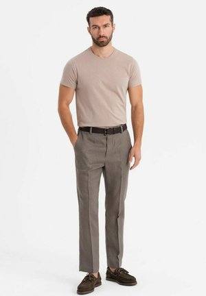Beige t-shirt, grå skräddarsydda byxor och bruna skor. Också har klädseln en slim fit med en jämn textur och minimala detaljer.