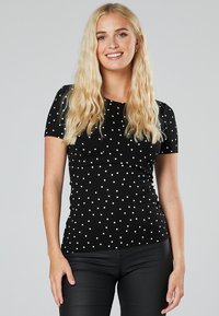 Schwarzes Polka-Dot-Oberteil mit kurzen Ärmeln, aus elastischem Stoff, mit einer schmal geschnittenen Passform und einem runden Ausschnitt.