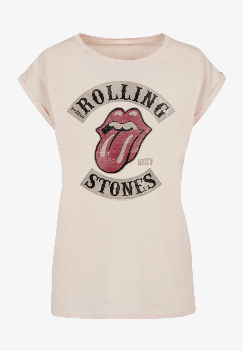 Pink T-shirt made of cotton featuring a black and red graphic of the Rolling Stones logo with a prominent tongue design and faded text.