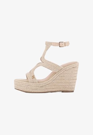 Sandalia de cuña beige con correas trenzadas texturizadas, hebilla en el tobillo y suela de plataforma. Presenta un diseño de cuerda apilada para mayor altura.