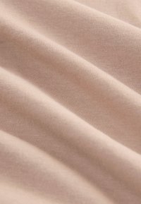 Light pink cotton fabric with soft texture, featuring gentle folds and a smooth, even surface. The lightweight material shows fine ribbing.
