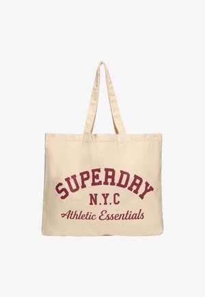 Sac en toile beige avec un texte incurvé rouge portant la mention "SUPERDAY N.Y.C Essentials Athlétiques." Il dispose de deux poignées robustes et d'une forme rectangulaire.
