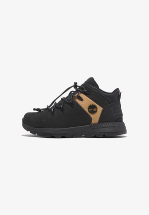 Zapatos de senderismo negros con un acento en tono marrón, que cuentan con una suela resistente, tejido duradero, cierre con cordones y un logo en el panel lateral.