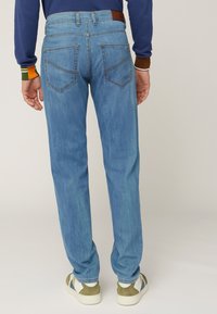 Jeans azzurri chiari con un design a gamba dritta. Presentano due tasche posteriori e cuciture a contrasto. Combinati con sneakers bianche e verdi oliva.