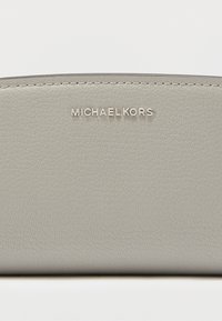 Γκρι πορτοφόλι από δέρμα με υφή, με ασημένια επωνυμία "MICHAEL KORS" στην πρόσοψη, με λεία επιφάνεια και απλό σχεδιασμό.