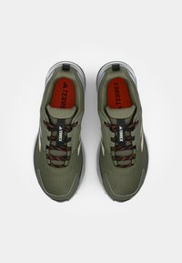 Grüne Sportschuhe mit Obermaterial aus Mesh und Synthetik, schwarzen Schnürsenkeln und roten Akzenten. Verfügt über einen gepolsterten Schaft und eine gepolsterte Sohle.