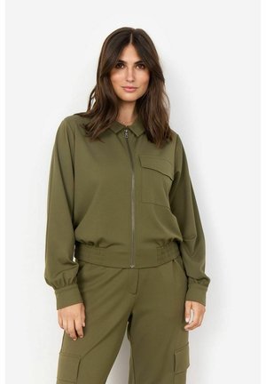 Veste zippée vert olive avec un col, une poche poitrine unique et une taille élastique. Fabriquée en tissu lisse avec des manches longues froncées.
