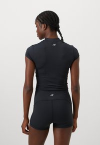 Top de sport noir à manches courtes et design ajusté, associé à un short noir assorti, avec des accents logo au dos.