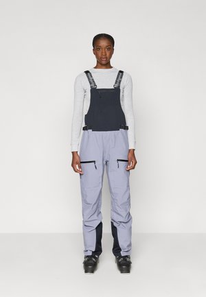 Tumesinine ja heledhalli värvi suusapüksid, millel on reguleeritavad rihmad, kaks ees olevat lukuga taskut ja sobiv disain talispordiks.