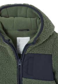 Green fleece jacket featuring a soft, textured exterior, a navy patch pocket, and a front zipper. Lined hood adds warmth. Care label visible.