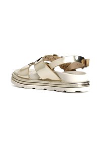 Gold metallic sandals with a thick white sole, featuring cross straps, cut-out details, and a adjustable back strap for secure fit.