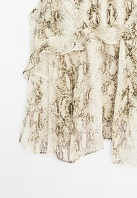 Lichtgewicht, gestructureerde stof in beige met een bruin slangenprintpatroon. Heeft geplooide lagen en een asymmetrische zoom.