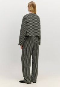 Zwart-wit gestreepte cropped jack en wijde broek, gemaakt van gestructureerde stof, met een open rug en een ontspannen pasvorm.