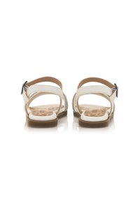 Sandalias blancas con suela plana, correa ajustable en el tobillo y acentos decorativos en los laterales. Plantilla texturizada con un diseño estampado.