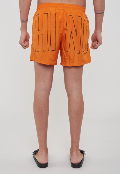 Costume da bagno arancione con un contorno nero e la scritta "HI NO" sul retro, dotato di cintura elastica e una texture leggera e liscia.