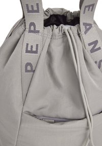 Zaino a corda grigio realizzato in tessuto spesso, con chiusura elastica superiore e spallacci grigi marchiati. Include una tasca con zip sulla parte frontale.