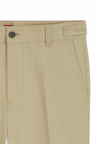 Pantaloni in cotone beige con vita piatta, due tasche laterali, chiusura con bottone e dettaglio logo ricamato in vita.