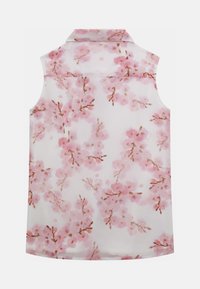 Blusa blanca sin mangas con estampado de flores de cerezo rosa y un cuello estándar, vista desde atrás sobre un fondo liso.