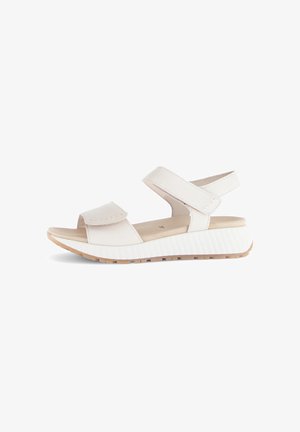 White sandal featuring adjustable straps, a cushioned sole, and a textured lightweight wedge heel. Flat rubber outsole for traction.
