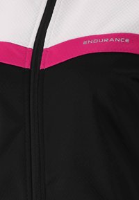 Svart och vit idrottsjacka med rosa detaljer. Har en dragkedja framtill och ordet "ENDURANCE" i silver på bröstet. Strukturerad tyg.