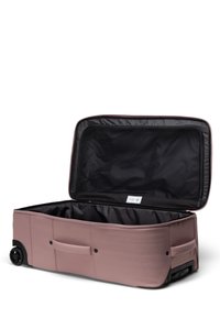 Měkký růžový kufr na kolečkách s velkým otevřeným oddílem a černýminteriérem. Obsahuje úchyty po stranách a zipové zapínání.