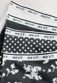 Quatre paires de sous-vêtements féminins empilées, avec des ceintures marquées "NEXT," en blanc, gris foncé, gris à pois blancs et gris à motif floral blanc.