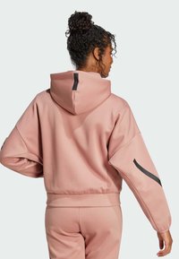 Sudadera con capucha rosa y corte relajado, que presenta un tejido texturizado, puños de canalé y detalles en negro en las mangas y la parte posterior.