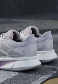 Paar hellgraue Sportschuhe aus strukturiertem Stoff mit "Duramo SL 2"-Markenlogo und dicken weißen gepolsterten Sohlen auf einer strukturierten Außenseite.