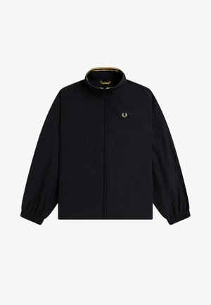 Chaqueta cortavientos negra con cremallera, puños elásticos, cuello alzado con ribete amarillo y pequeño logo de laurel dorado en el lado izquierdo del pecho.