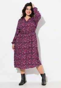 Vestido midi de manga larga con un patrón floral en rosa, con cinturilla elástica y escote en V; combinado con botas negras con tachuelas hasta el tobillo.
