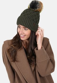 Knit olive green beanie with a textured pattern, featuring a multicolored faux fur pom-pom on top. Leather logo accent on the side.