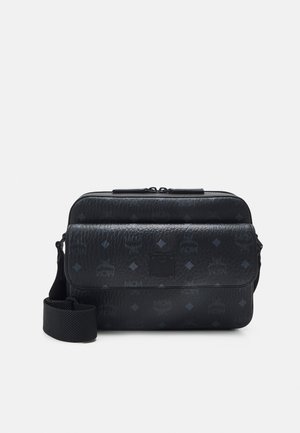 Sac messager en cuir noir avec logo embossé et motif en diamant, doté d'une fermeture à glissière sur le dessus et d'une bandoulière réglable.