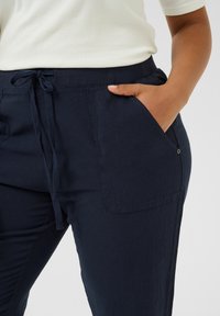 Pantalones livianos de color azul marino, hechos de tela suave. Cuentan con una cinturilla elástica con cordón, bolsillos laterales y un corte relajado.