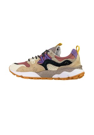 Sneaker multicolore con pannelli in camoscio beige, nero, viola e marrone, suola con motivo, lacci neri e linguette gialle su sfondo bianco.