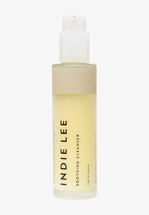 Clear bottle with a frosted finish, light yellow liquid inside. White pump top, label features black text on a beige band.