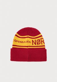 Bonnet tricoté rouge avec des rayures jaunes et un texte disant "Copenhagen NØR". Présente un revers replié et une texture côtelée.